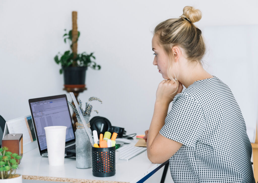 Young woman concentrating on a laptop in a modern office setting.