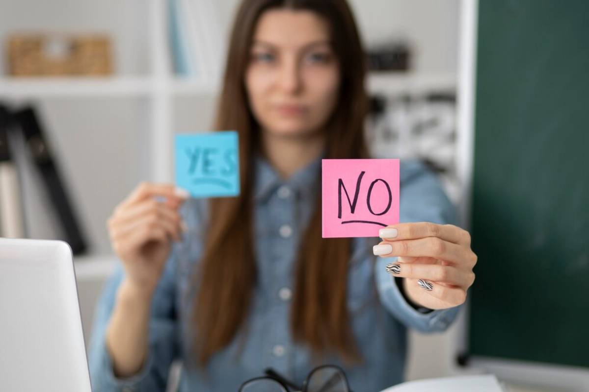 A woman holding sticky notes with YES and NO written on them, sitting at a desk.
